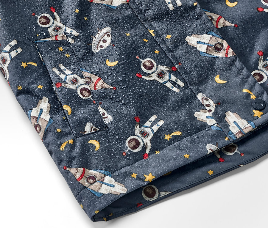 Detailaufnahme einer dunkelblauen Kinder-Thermo-Regenjacke mit Astronauten-, Raketen- und Sternenmuster.