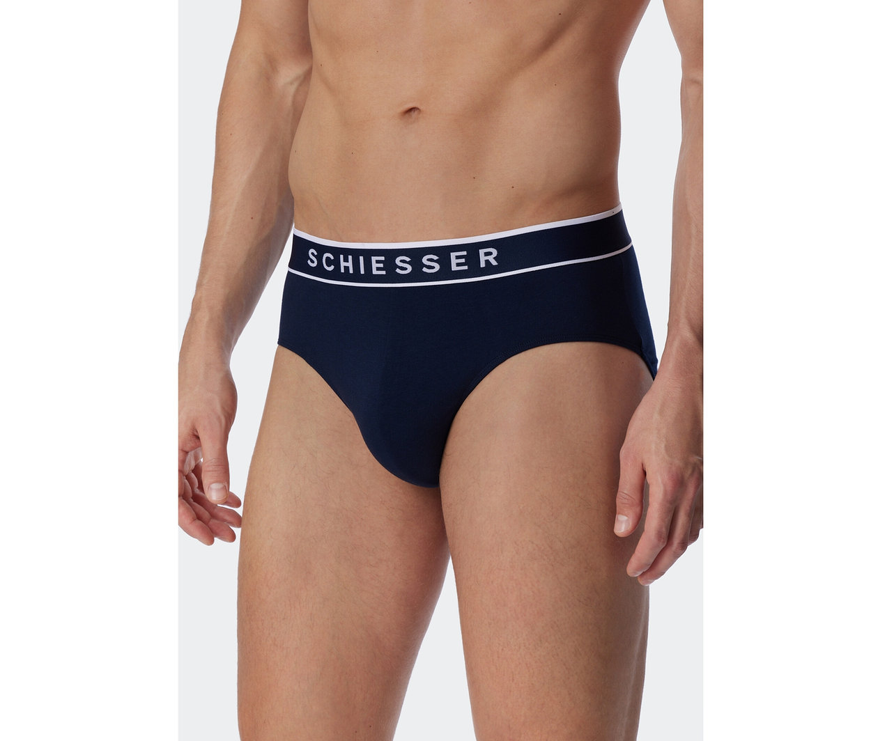 Mann trägt dunkelblaue SCHIESSER Rio-Slips mit weißem Bund und SCHIESSER-Schriftzug.