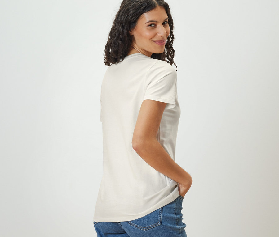 Frau blickt über die Schulter und trägt ein weißes Basic T-Shirt.