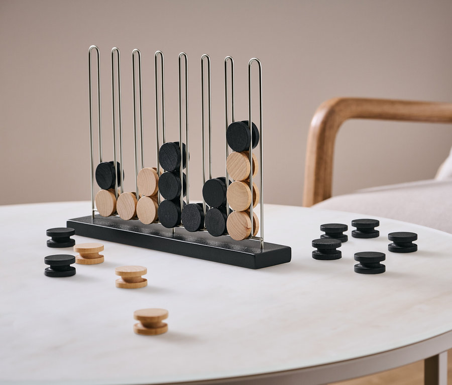 Spiel »4 in einer Reihe« mit schwarzen und hellbraunen Spielsteinen auf einem Tisch.
