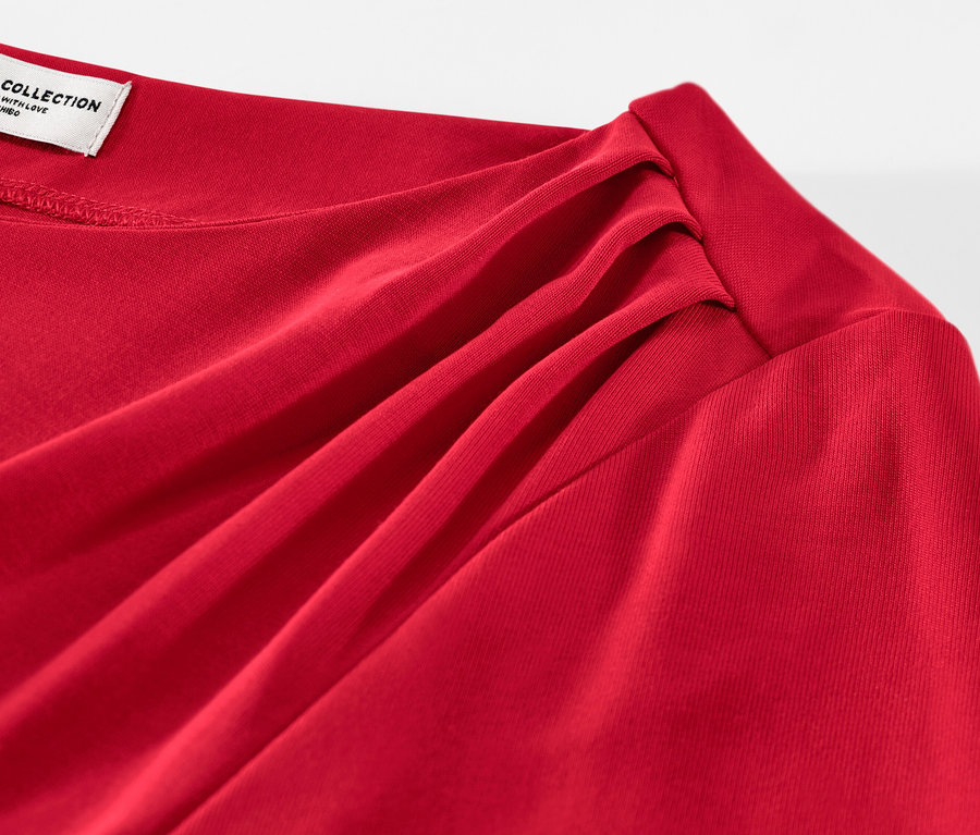 Detailansicht eines roten Blusenshirts mit Raffung.