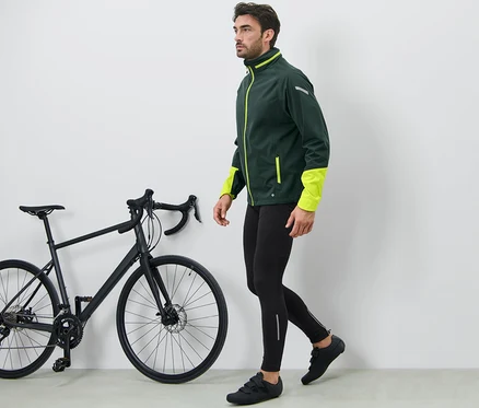 Mann geht neben schwarzem Fahrrad und trägt eine Fahrradhose.