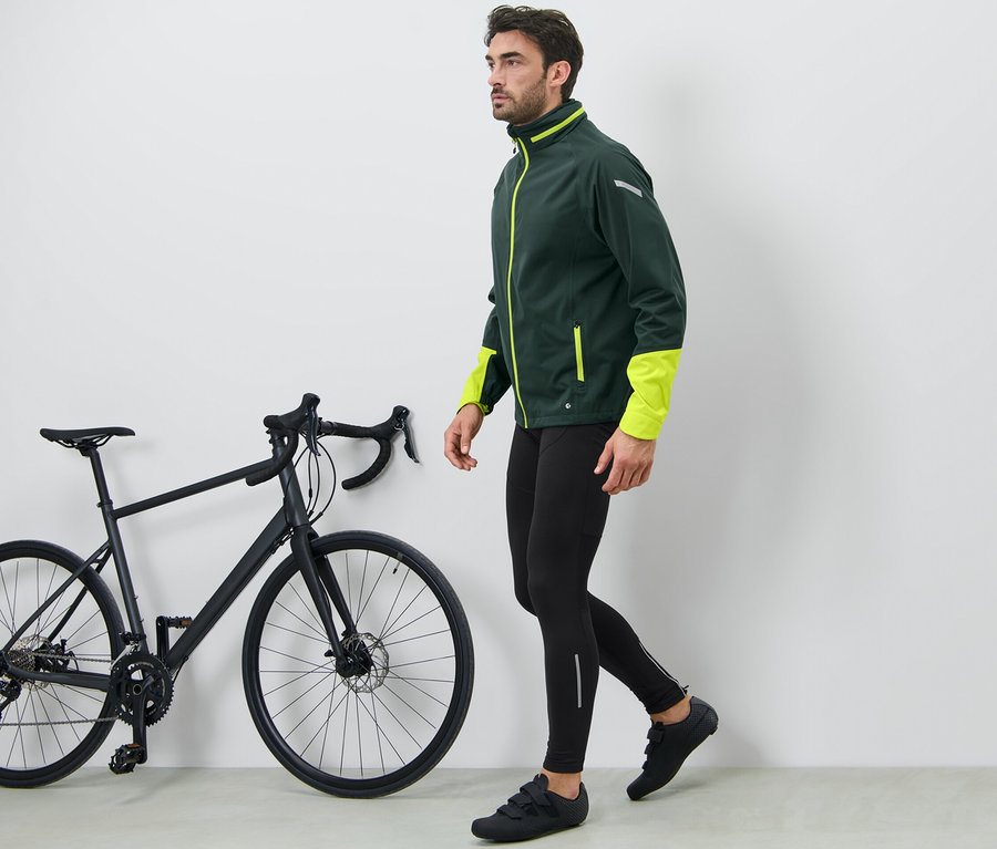 Mann geht neben schwarzem Fahrrad und trägt eine Fahrradhose.