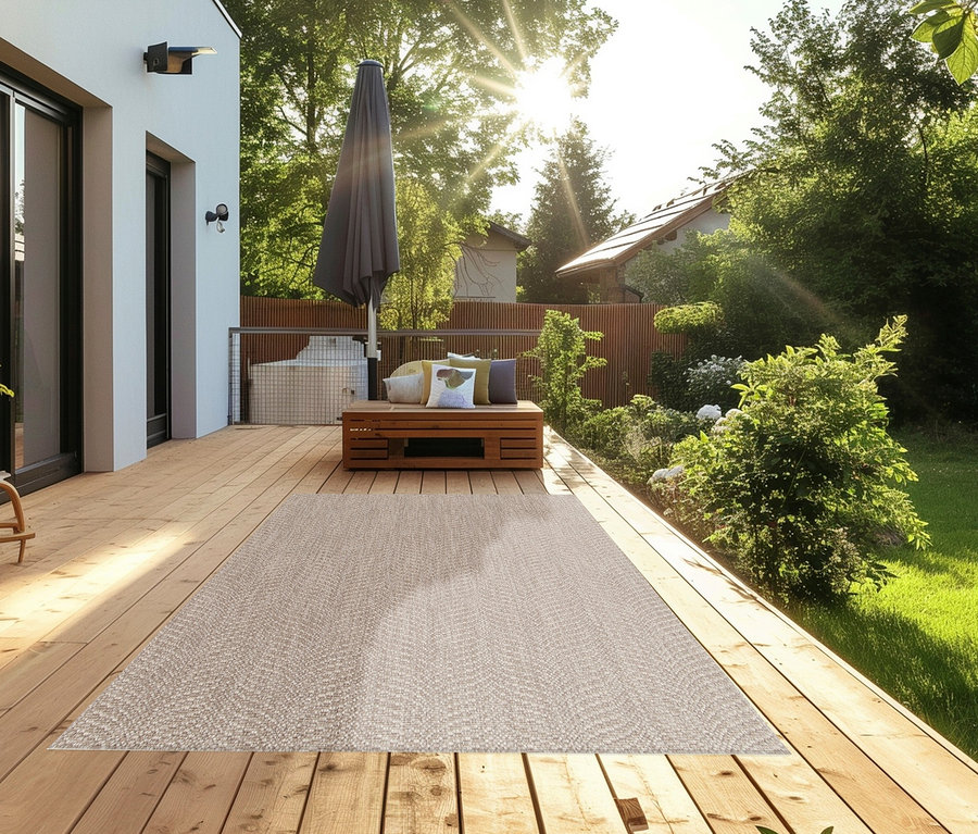 Auf einer Holzterrasse liegt ein beiger Teppich »Twine« natural flow.