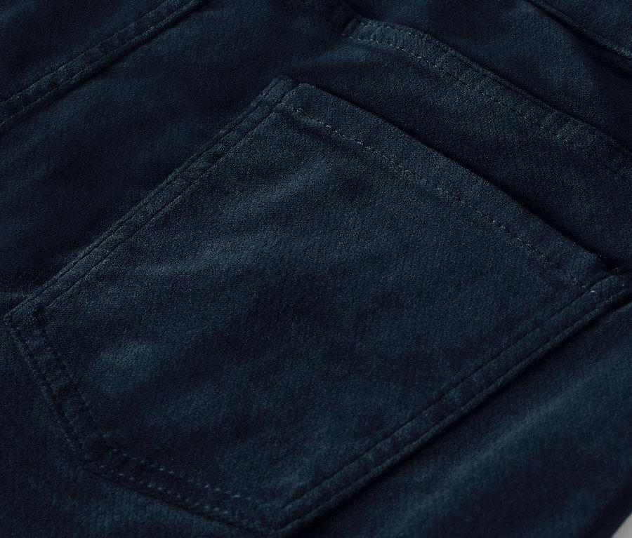 Detail einer Gesäßtasche einer dunkelblauen Cordhose.