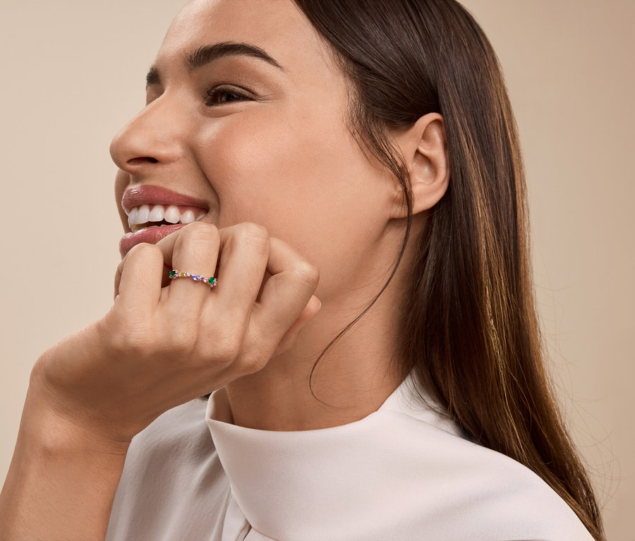Frau lächelt, stützt ihr Kinn mit der Hand und trägt einen Ring am Finger.