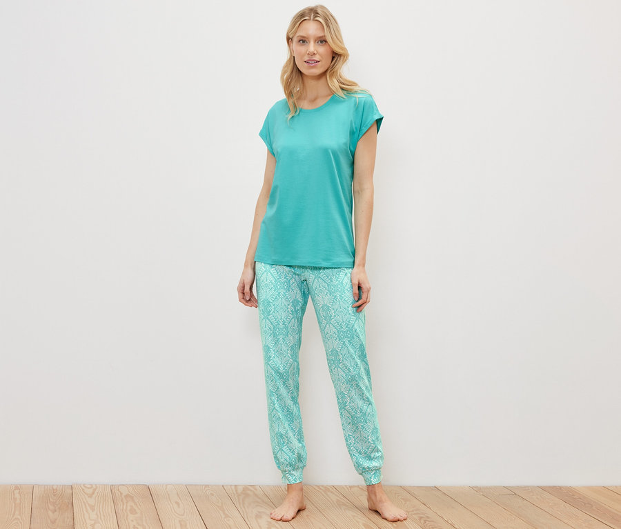 Blonde Frau steht in einem Pyjama-Set.