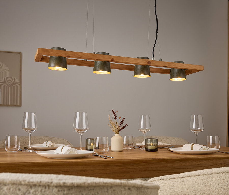 Vier graue Lampen über einem Holztisch mit Gedecken und Gläsern.