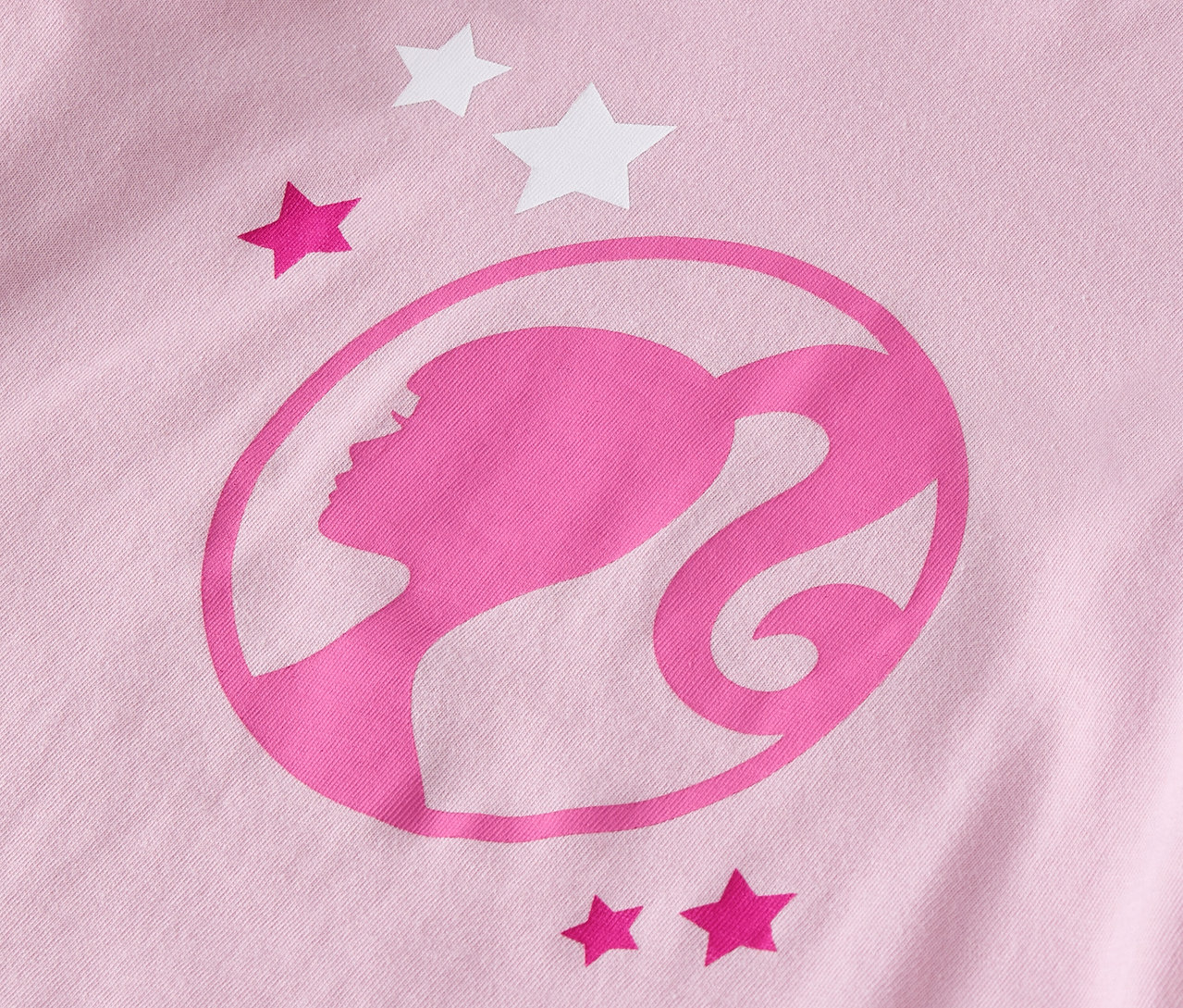 Detailansicht eines rosafarbenen T-Shirts mit Barbie-Logo und Sternen.
