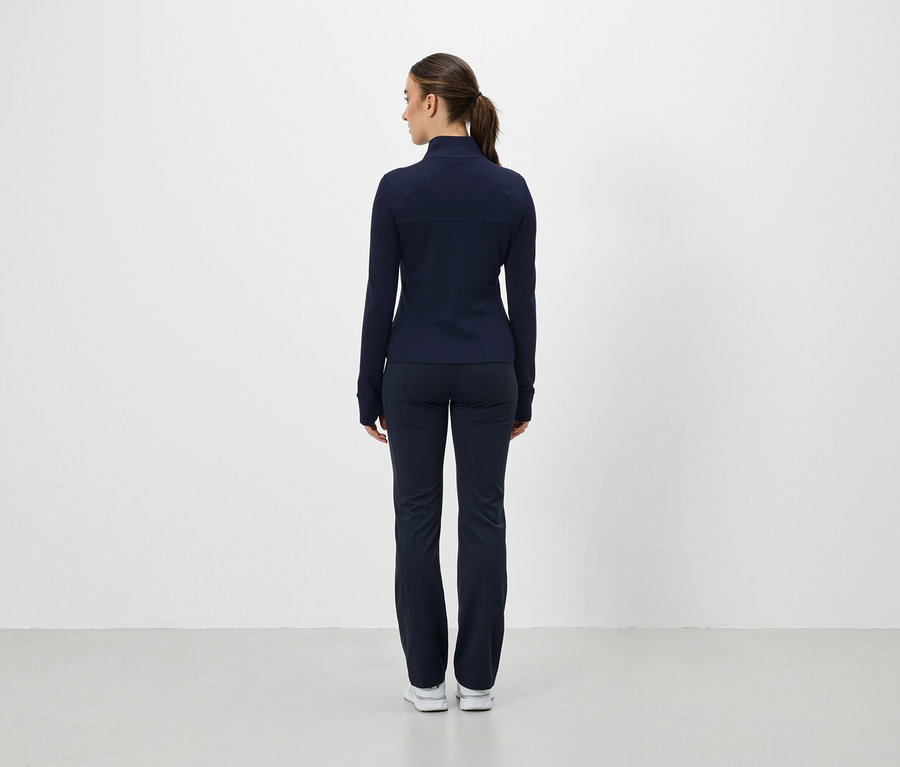 Frau mit dem Rücken zur Kamera trägt eine dunkelblaue Sportjacke und -hose.