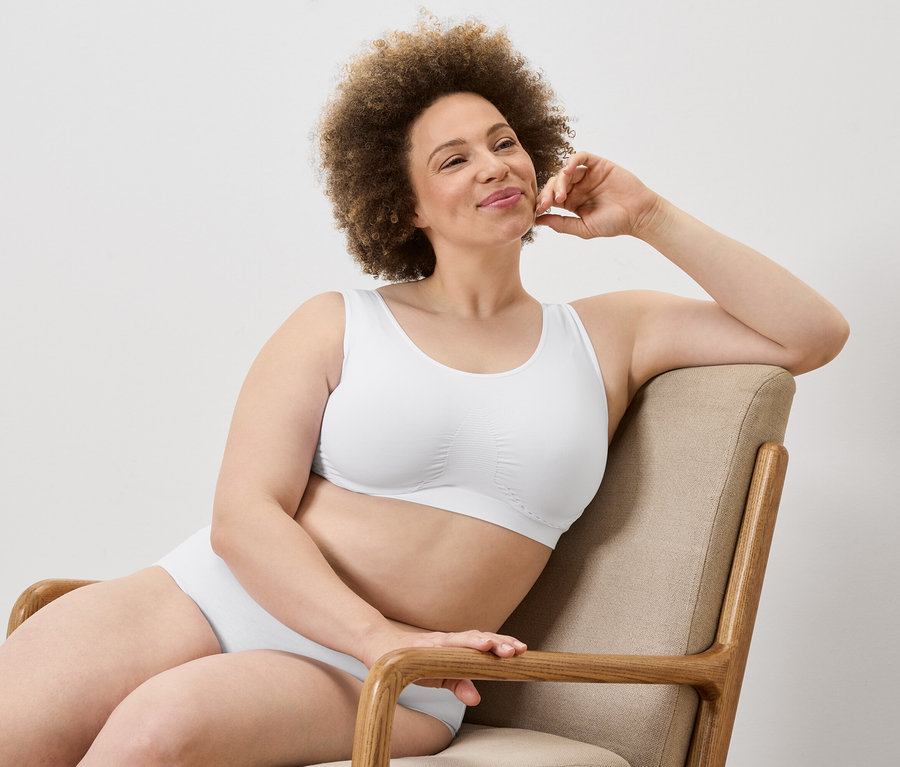 Frau mit Afro sitzt in einem Sessel in weißem BH und Unterhose.