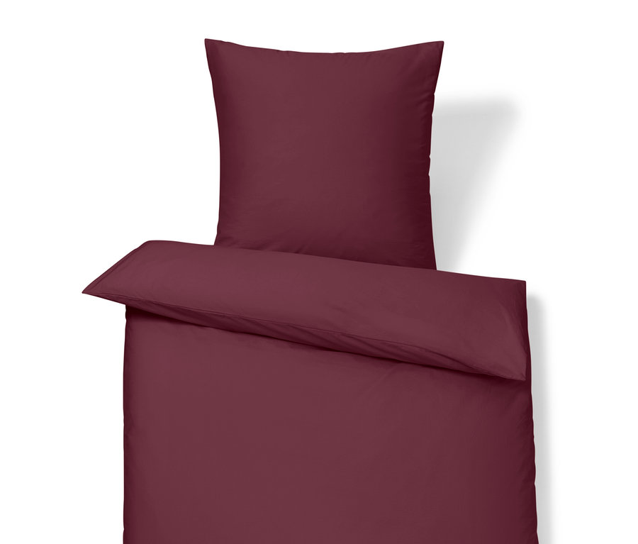 Weinrote Bettwäsche mit Kissen und Bettdecke.