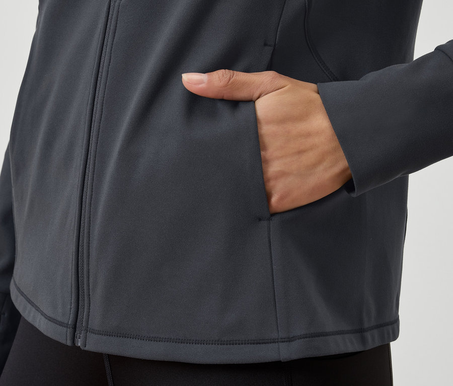 Detailansicht einer grauen Reißverschlussjacke mit einer Hand in der Tasche.