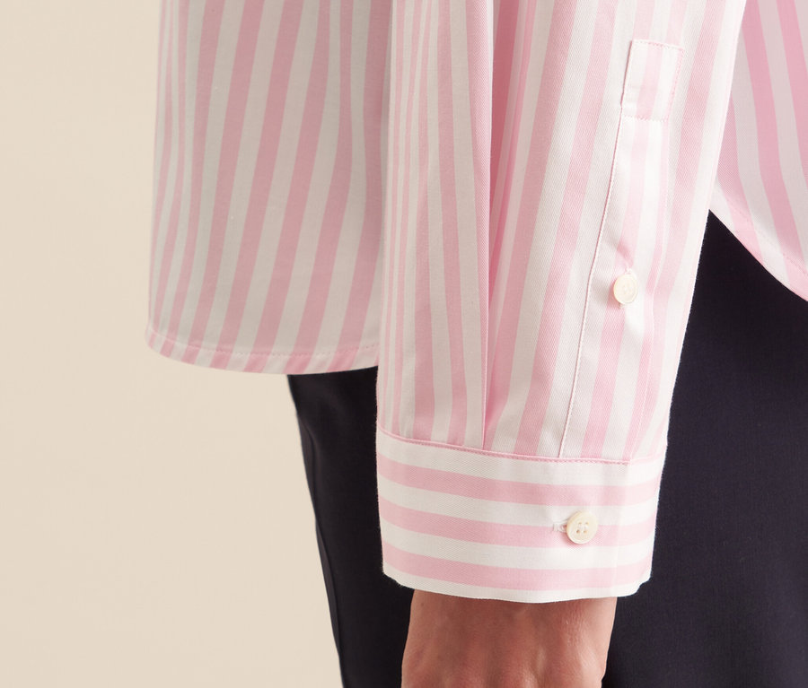 Detailaufnahme einer Seidensticker Oversize Hemdbluse in Rosé mit weißen Streifen, am Arm einer Frau.