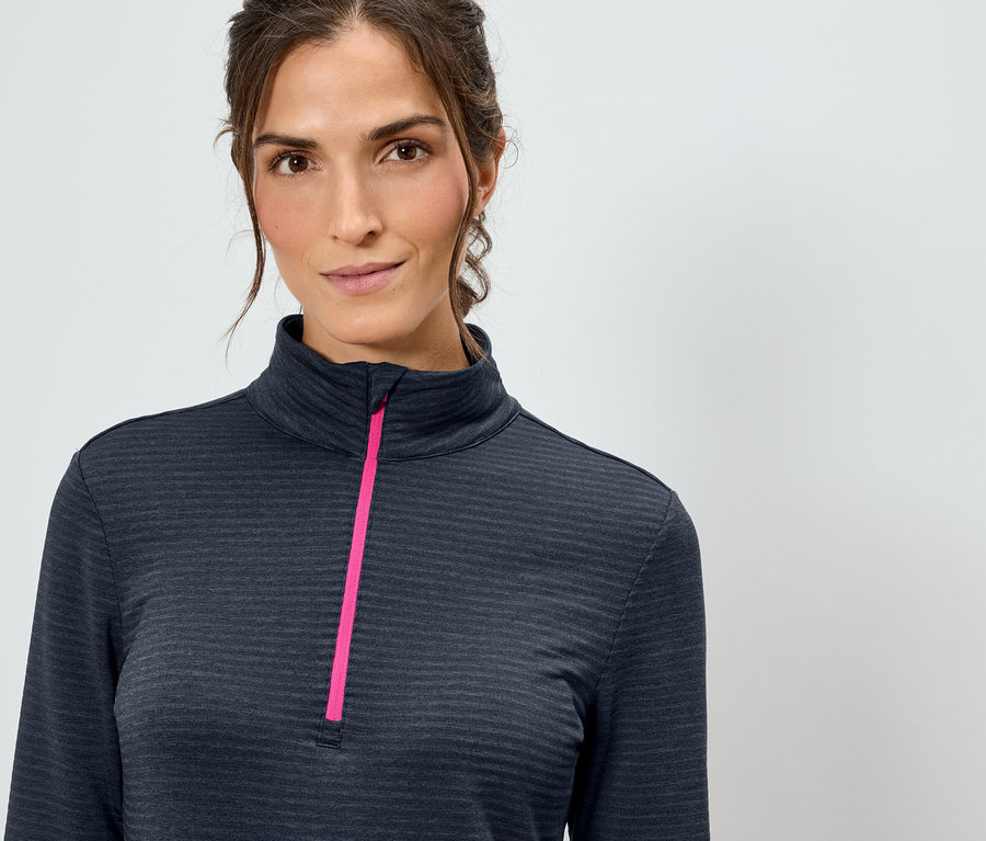 Frau trägt ein dunkelblaues, langärmliges Oberteil mit einem pinkfarbenen Reissverschluss.