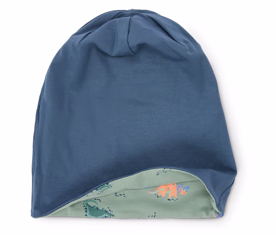 Blaues, gewendetes Mützchen mit Dinosaurier-Muster auf der Innenseite.