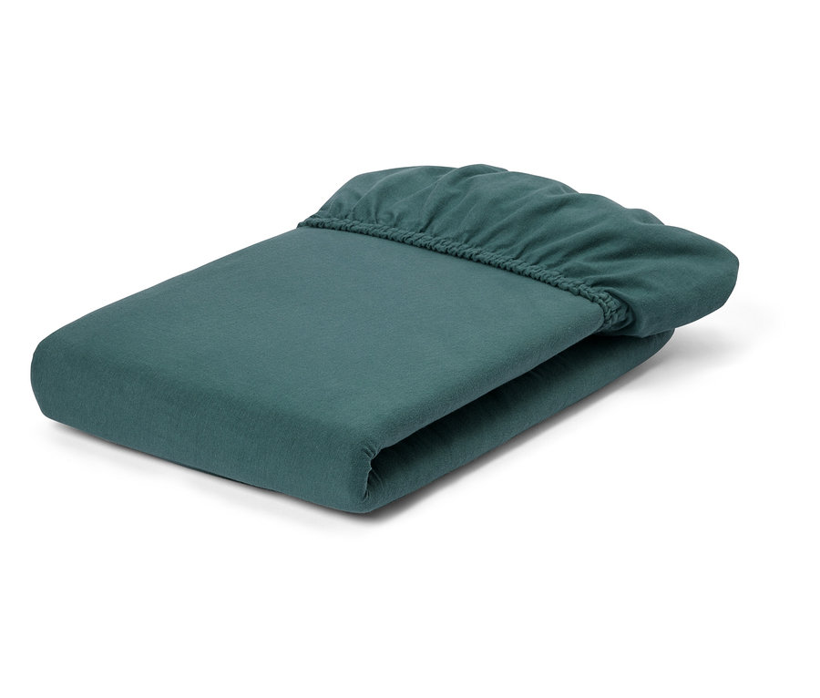 Ein gefaltetes, petrolfarbenes Spannbettlaken liegt auf einem weißen Hintergrund.