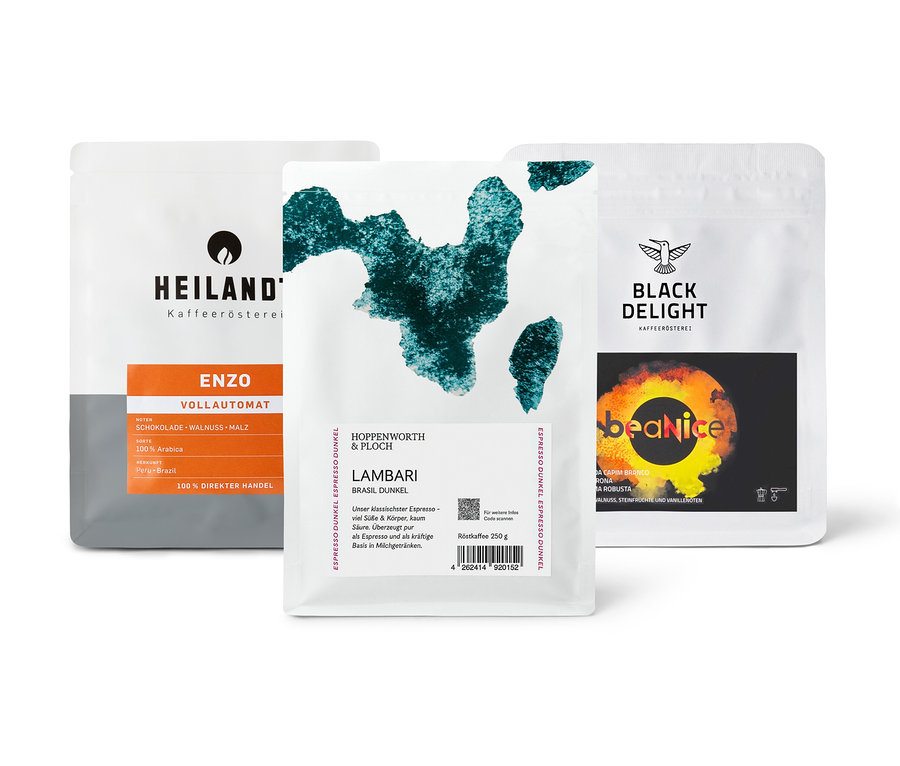 Drei Kaffeepackungen des "Vollautomaten Probierpaket "Caffè Crema Entdecker Set" - 3x 250 g Ganze Bohne" liegen auf einem Tisch.