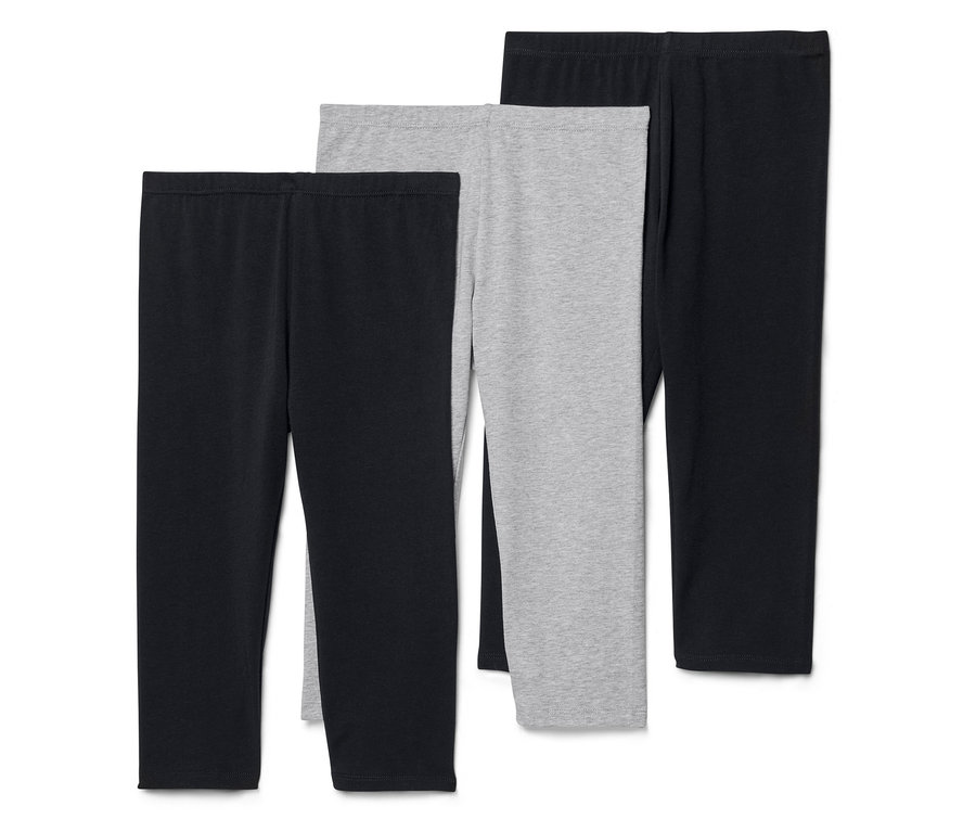 Drei Leggings, zwei schwarz und eine grau, liegen nebeneinander.