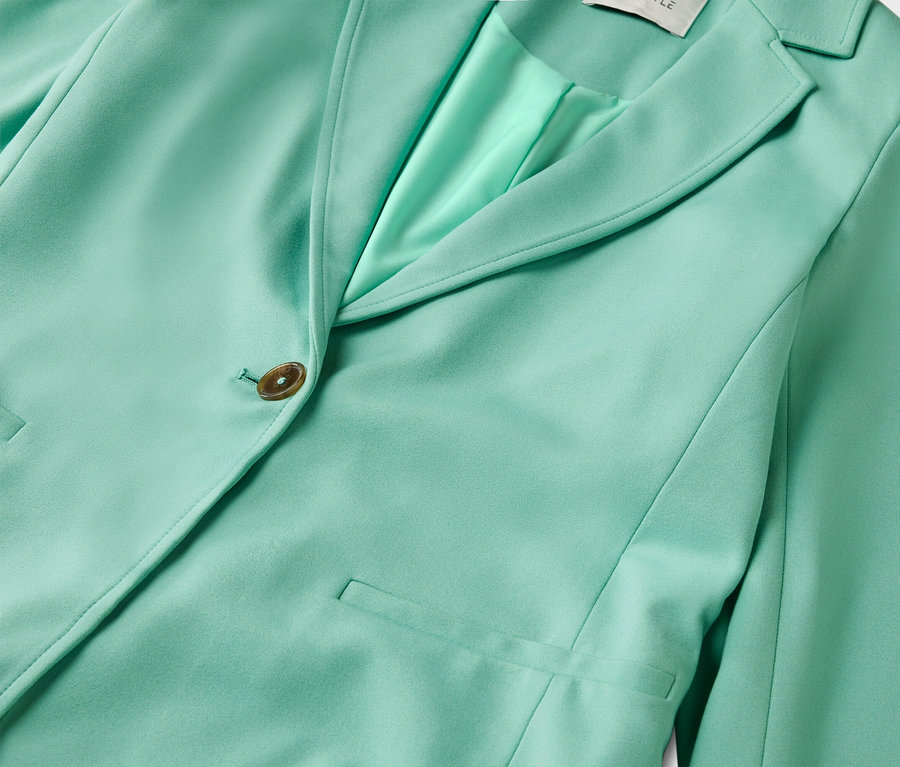 Nahaufnahme eines mintgrünen Blazers mit Knopf und Taschen