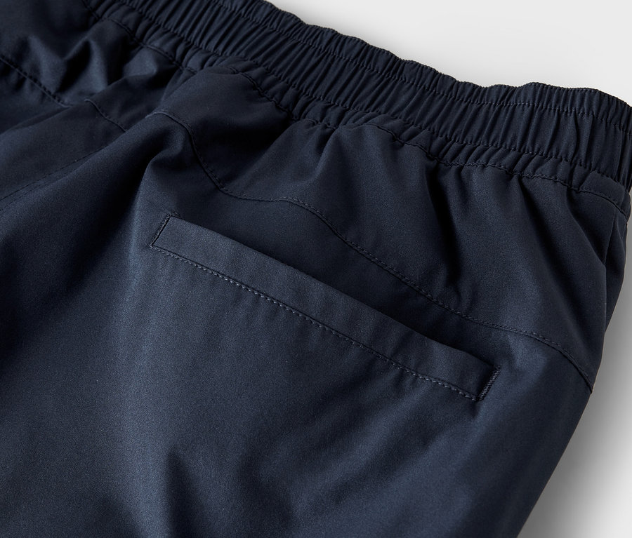 Detailaufnahme einer marineblauen Trainingshose mit elastischem Bund und Gesäßtasche.