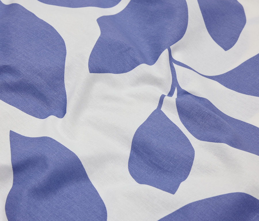 Nahaufnahme eines Stoffes mit blauem Blättermuster auf weißem Grund.