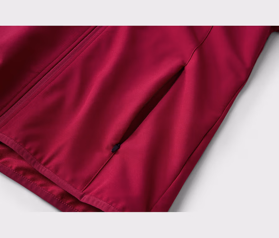 Nahaufnahme einer dunkelroten Jacke mit einem diagonalen Reißverschluss auf der linken Seite und einer diagonalen Tasche mit Reißverschluss auf der rechten Seite.