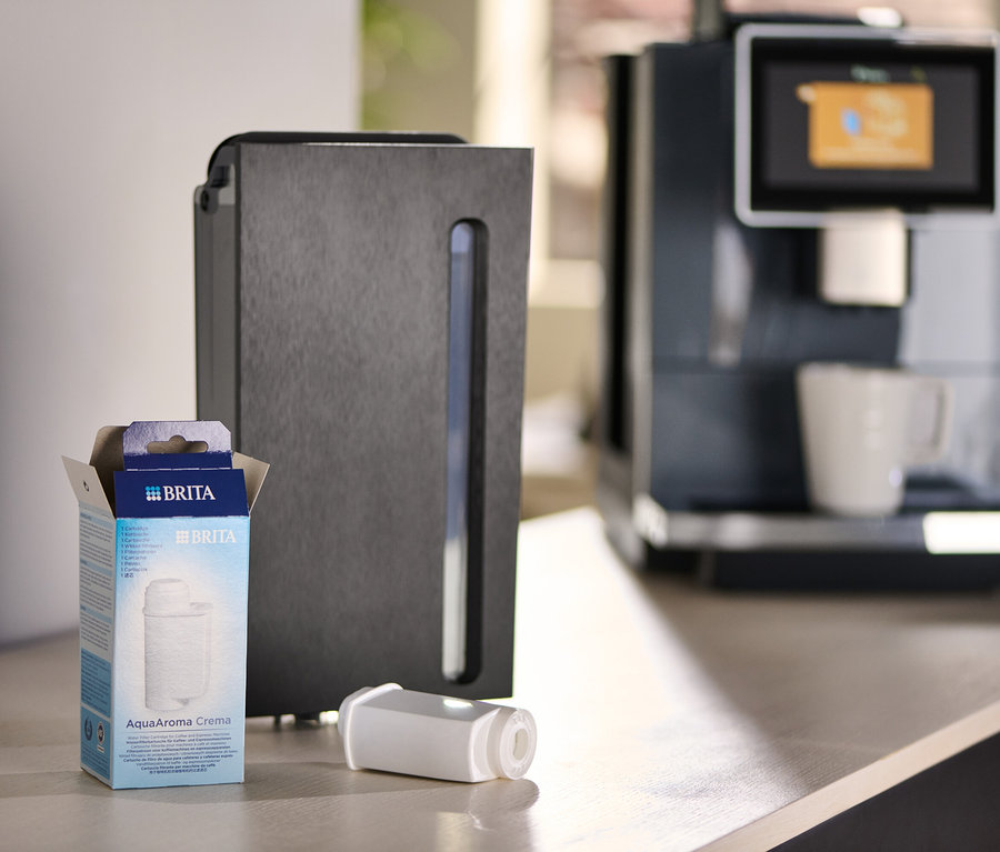 Eine Packung Brita AquaAroma Crema Filter neben einem Filter und einer Kaffeemaschine.