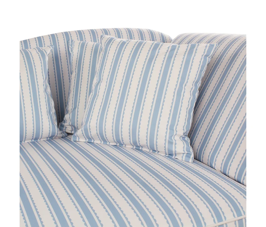 Nahaufnahme eines Sofas mit hellblau-weiß gestreiftem Stoffbezug und passenden Zierkissen. Die blauen Streifen haben einen gewellten Rand.