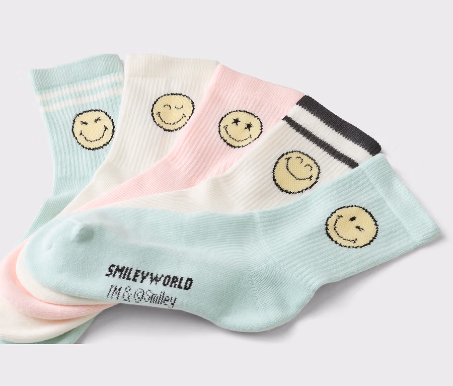 Fünf Socken in Pastellfarben mit Smiley-Motiven liegen übereinander. Die Socken sind hellblau, weiß und rosa.