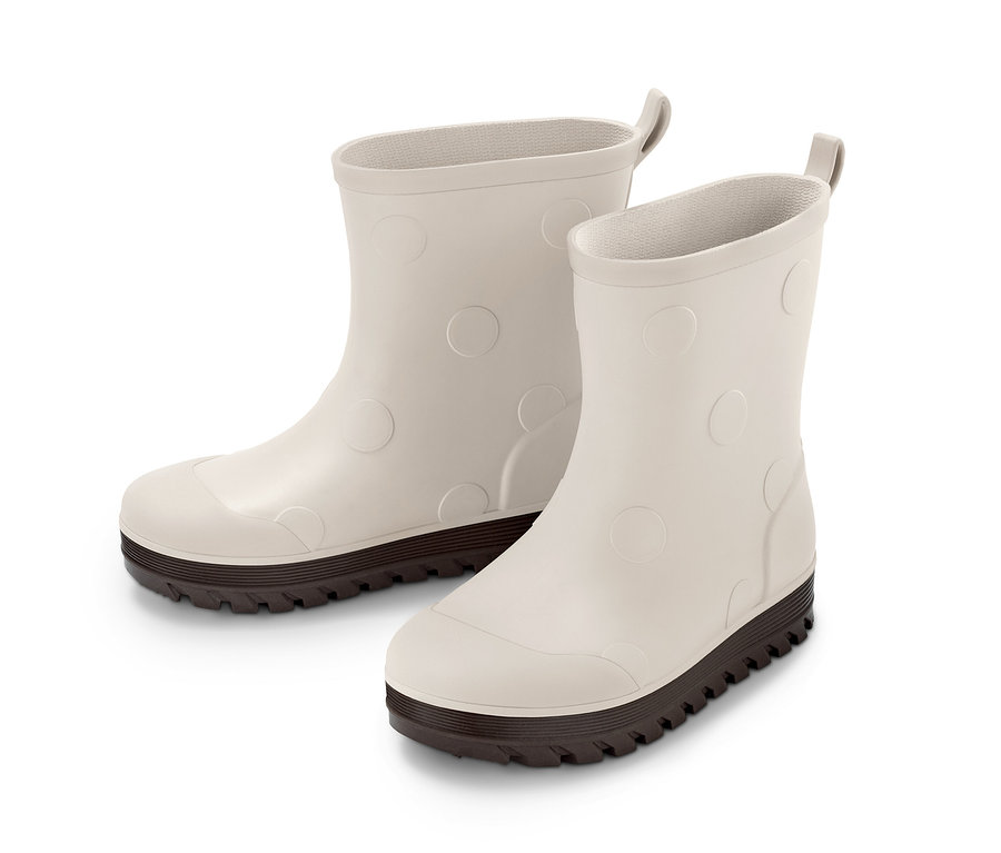 Zwei Gummistiefel mit dunklen Sohlen und erhabenen Kreisen auf hellgrauem Untergrund.