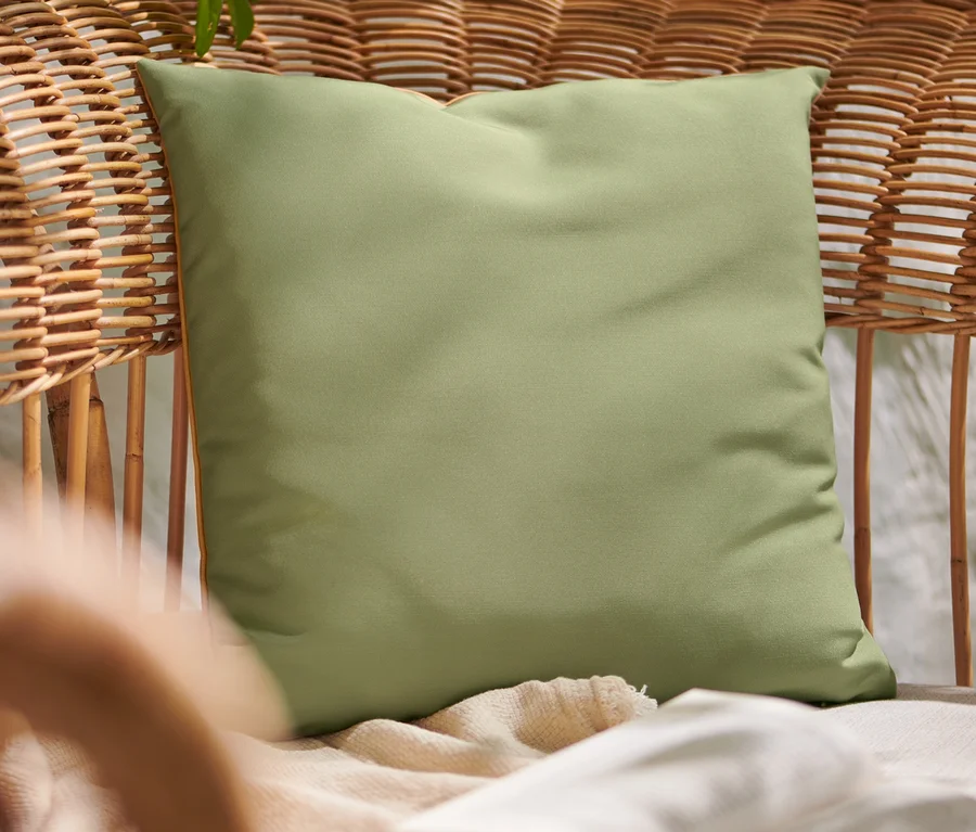 Grünes Outdoor-Kissen auf einem Rattansessel.