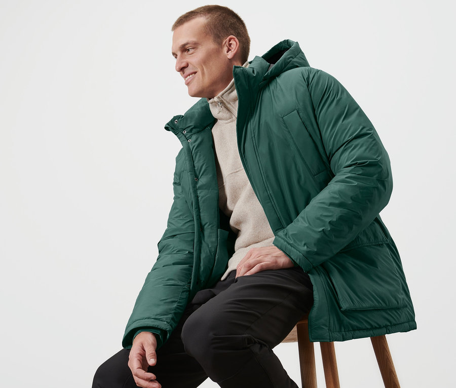 Mann sitzt auf einem Hocker und trägt eine Steppparka.