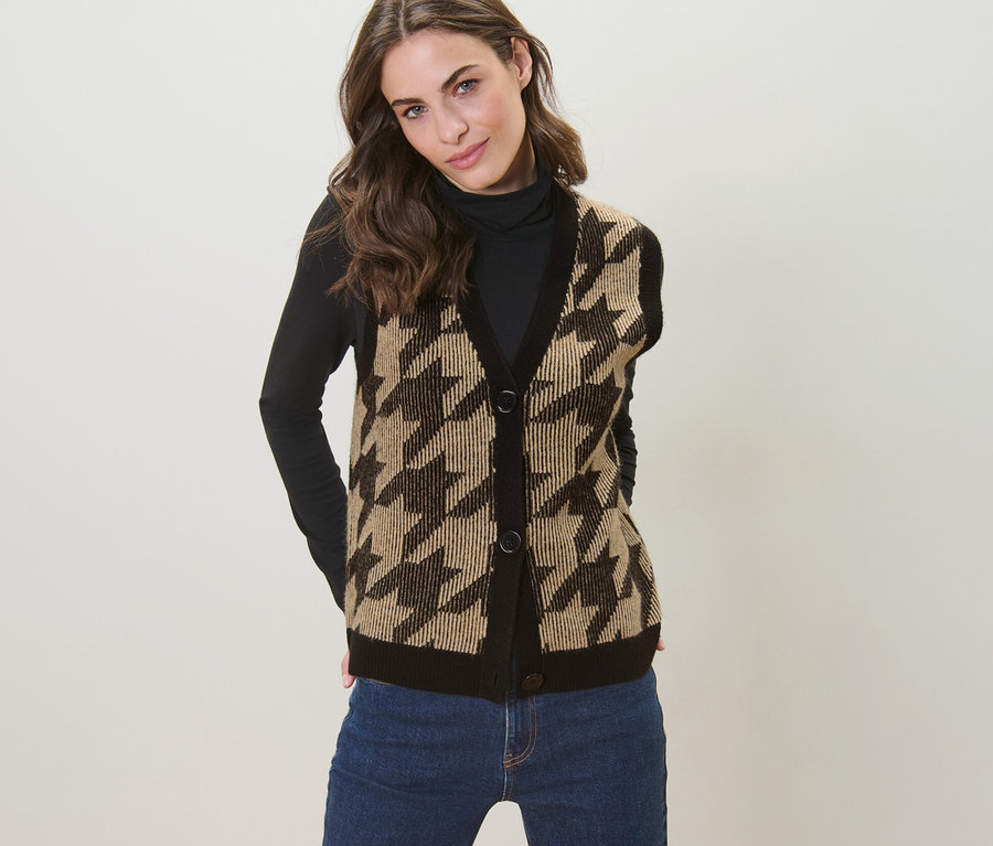 Frau posiert in Strickweste mit Hahnentritt-Jacquard.