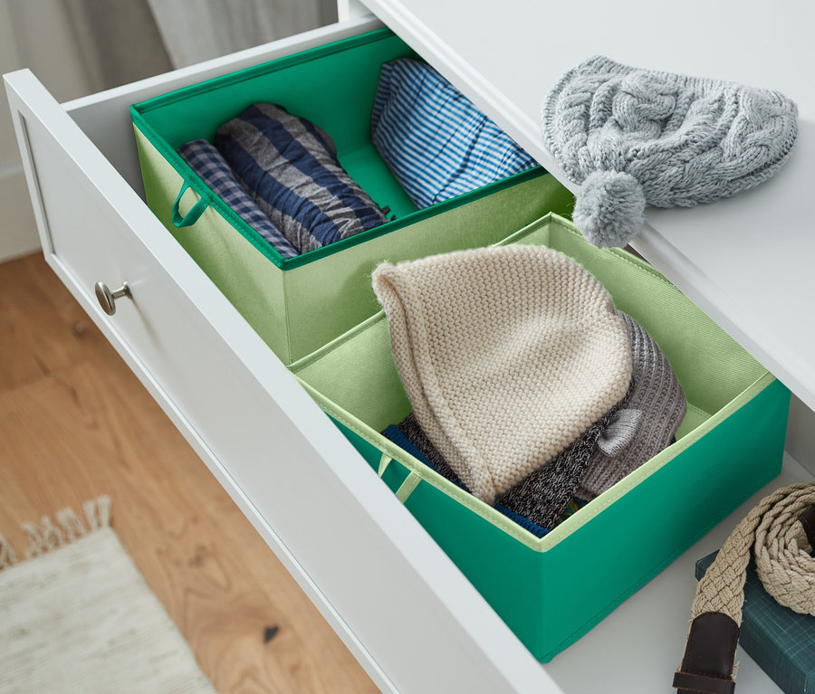 Eine offene Schublade einer weißen Kommode enthält zwei große Schubladen-Ordnungsboxen und Kleidung.