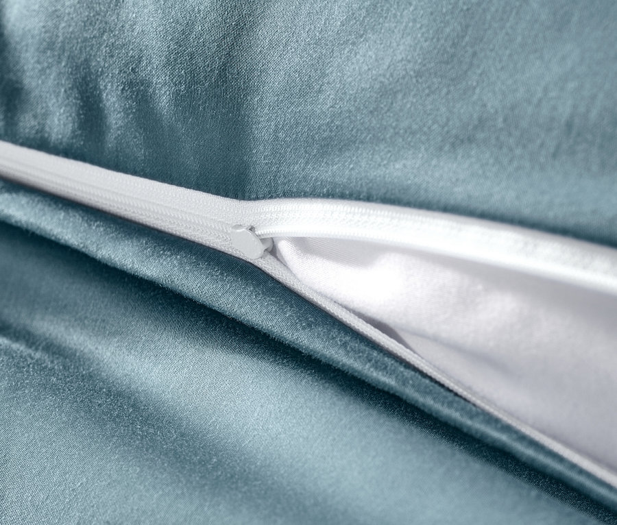 Detailaufnahme von blauer Baumwollsatin-Bettwäsche mit weißem Reißverschluss.