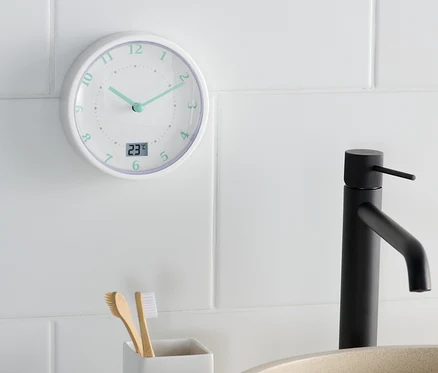 Eine Badwanduhr zeigt 11:22 Uhr neben einem Waschbecken und einem Zahnbürstenhalter.