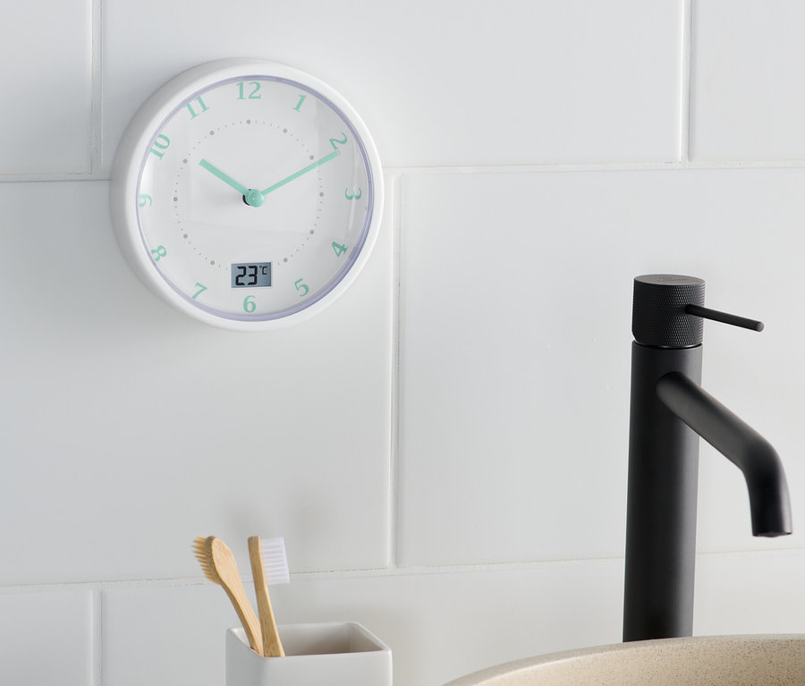 Eine Badwanduhr zeigt 11:22 Uhr neben einem Waschbecken und einem Zahnbürstenhalter.