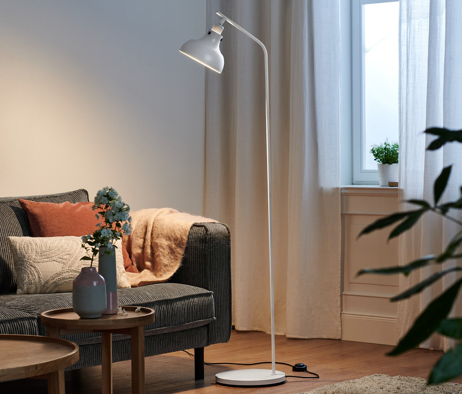 Im Wohnzimmer steht eine Stehleuchte aus Metall neben einem grauen Sofa.
