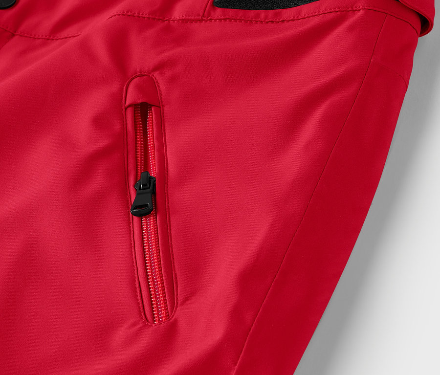 Detail einer roten Jacke mit schwarzem Taschenreißverschluss.