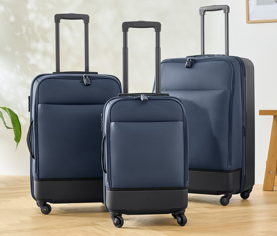 Drei Hybridkoffer (klein, mittel und groß) stehen auf einem Holzboden.