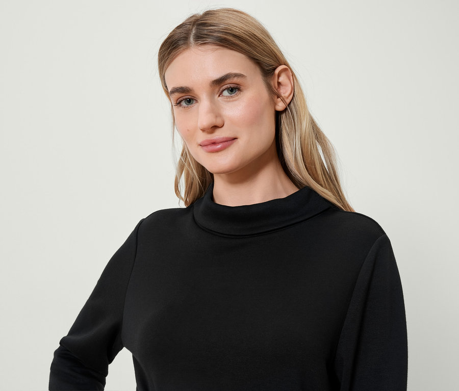 Porträt einer blonden Frau in einem schwarzen Rollkragenpullover.