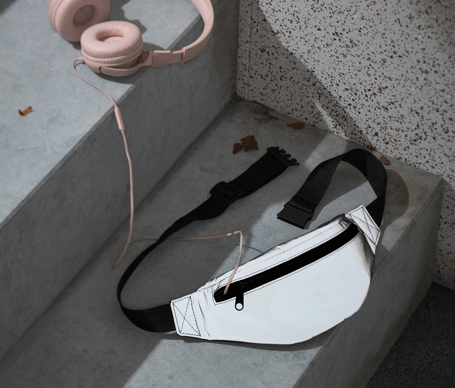 Rosa Kopfhörer und eine Hüfttasche aus recyceltem Material liegen auf Stufen.