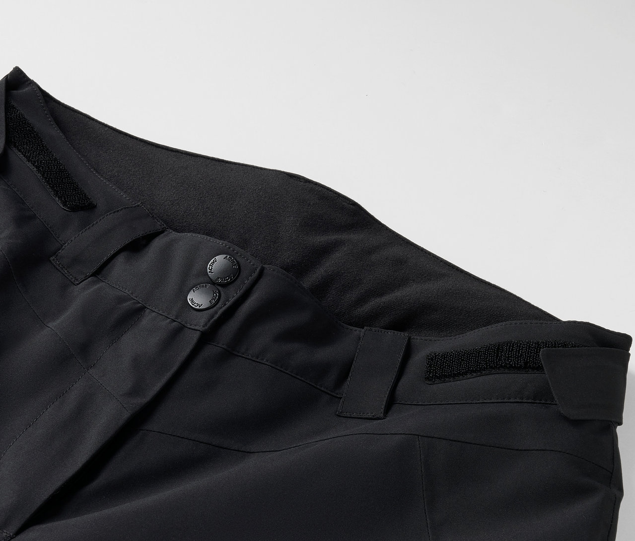 Detailaufnahme einer schwarzen Hose mit Knöpfen und Gürtelschlaufen.