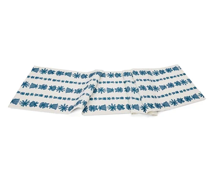 Weißer Tischläufer mit blauem Muster aus Blumen und geometrischen Formen.