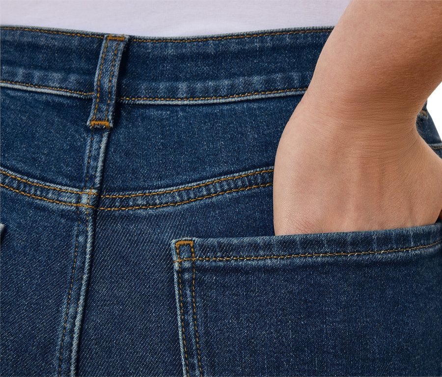 Detailansicht der Rückseite von blauen Jeans mit einer Hand in der Tasche.