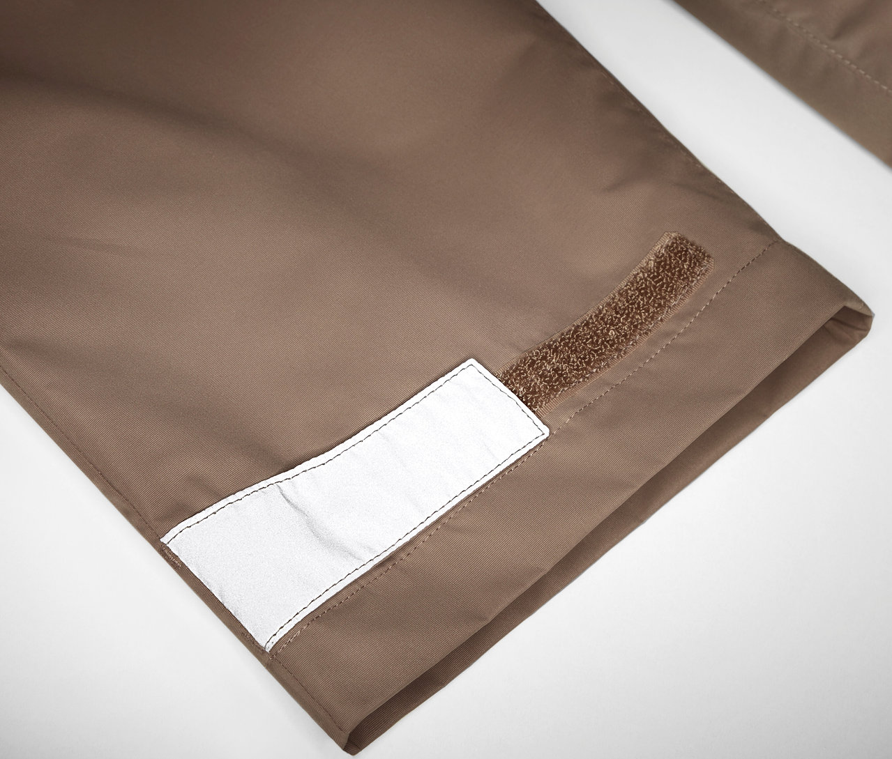 Detail einer Kinder-Regenhose mit Reflektor und Klettverschluss.