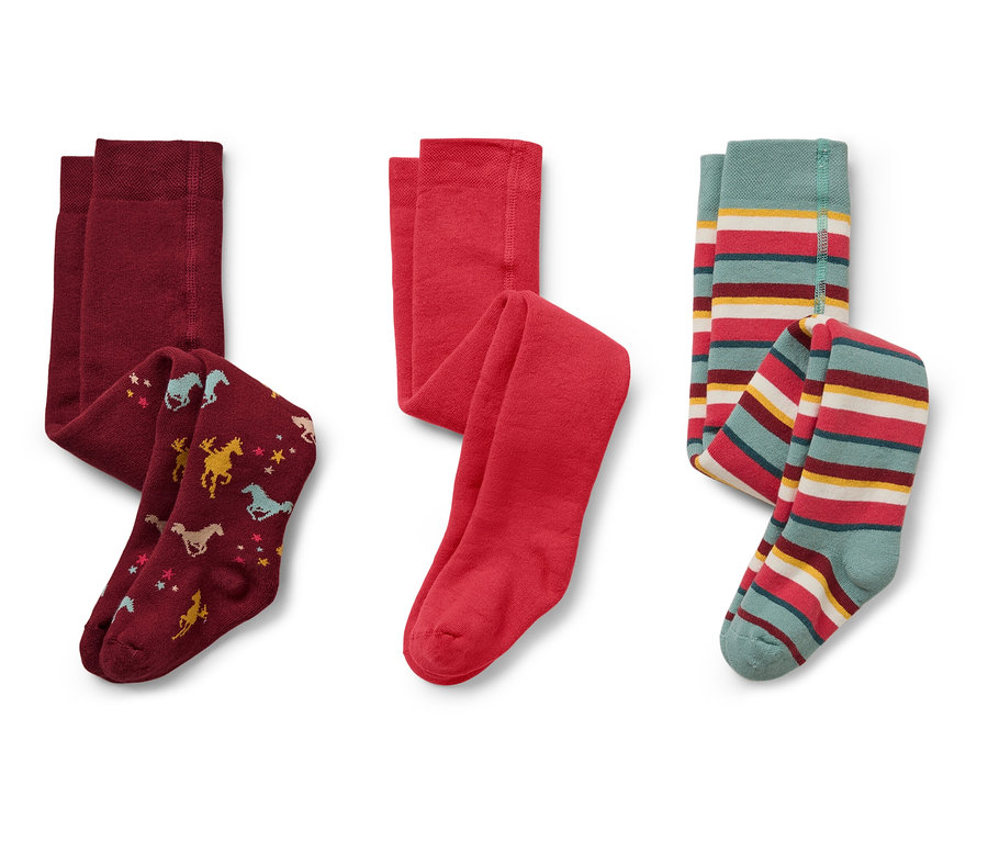 Auf einem weißen Hintergrund liegen drei Kinderstrumpfhosen: bordeauxrot mit Pferden und Sternen, rot und gestreift mit Türkis, Rot, Gelb und Weiß.