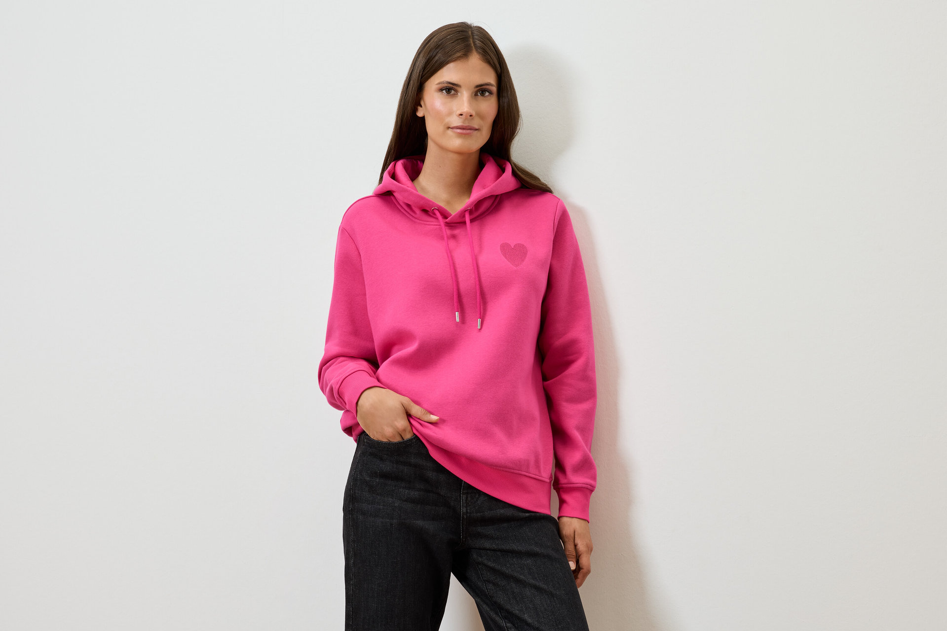 Frau trägt einen pinken Hoodie und schwarze Jeans.