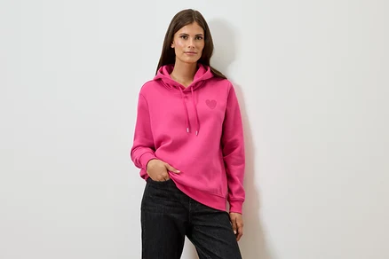 Frau trägt einen pinken Hoodie und schwarze Jeans.